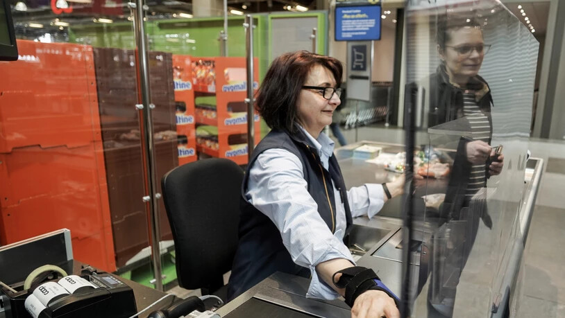 Detailhandel schützt Kunden und Angestellte: Eine Coop-Kassiererin hinter einer Plexiglasscheibe in der Filiale am Bahnhof von Biel.