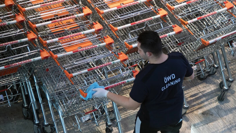 Ein Mitarbeiter eines Ladens in Salzburg desinfiziert Einkaufswagen. (Archivbild)