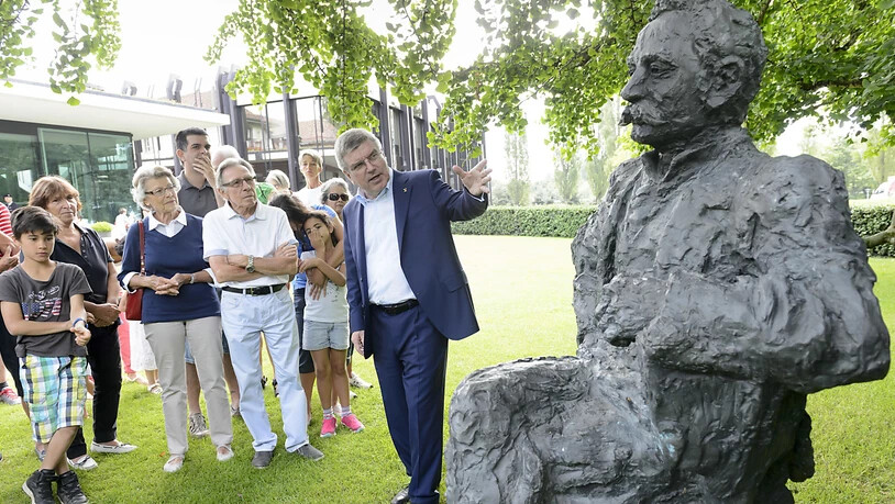 IOC-Präsident Thomas Bach neben einer Statue von Pierre de Coubertin, dem "Erfinder" der modernen Olympischen Spiele