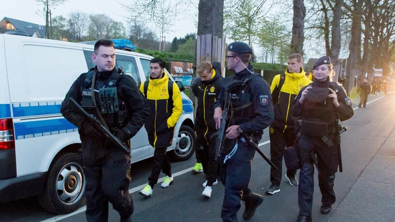 Sichtlich geschockt werden BVB-Spieler nach dem Sprengstoffanschlag auf ihren Mannschaftsbus von Polizisten bewacht und begleitet