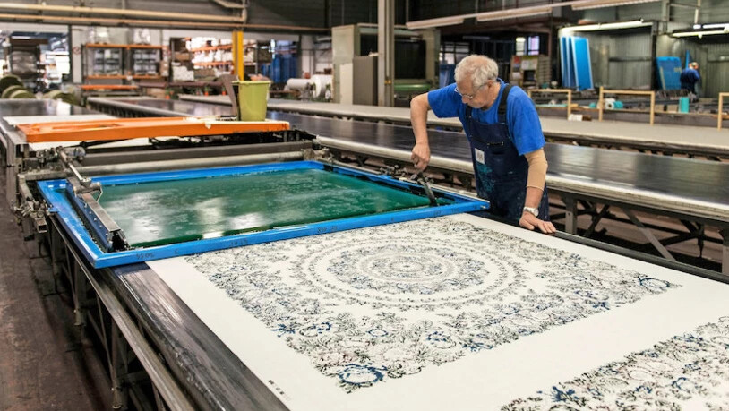 Ein präzises Handwerk: Ein Mitarbeiter verteilt Farbe auf einem Drucksieb für ein Foulard.
