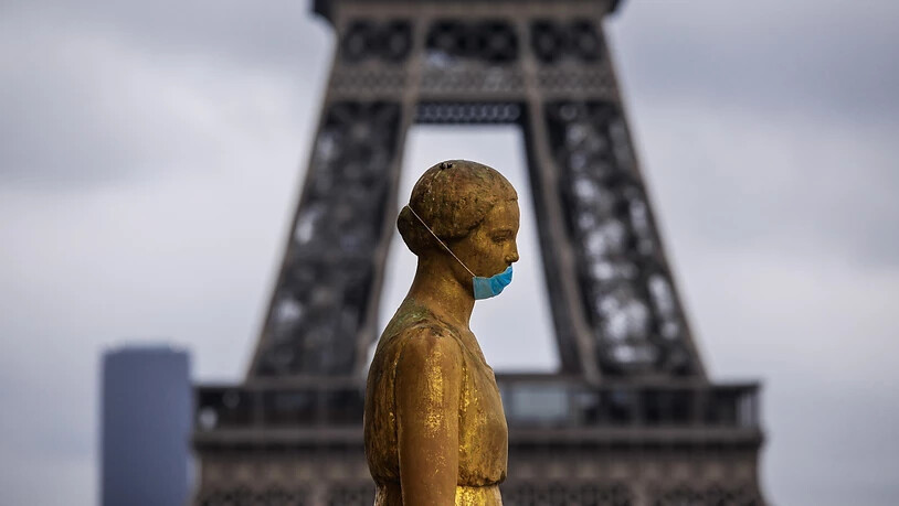 Eine goldene Statue am Pariser Platz Trocadéro trägt eine Schutzmaske. Im Hintergrund ist das berühmte Wahrzeichen Eiffelturm zu sehen. (Archivbild)