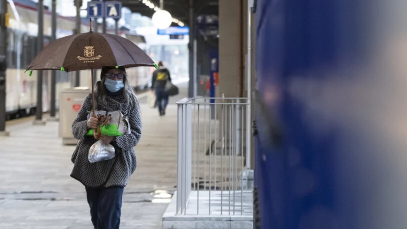 Eine Frau mit Hygienemaske läuft das Perron beim Bahnhof Locarno entlang. (Archivbild)