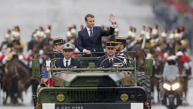 ARCHIV - Der französische Präsident Emmanuel Macron (M) wird in einem Militärfahrzeug bei einer Parade über die Champs-Elysees in Paris gefahren. Frankreich verzichtet wegen der Corona-Krise auf die traditionelle Militärparade am Nationalfeiertag 14…