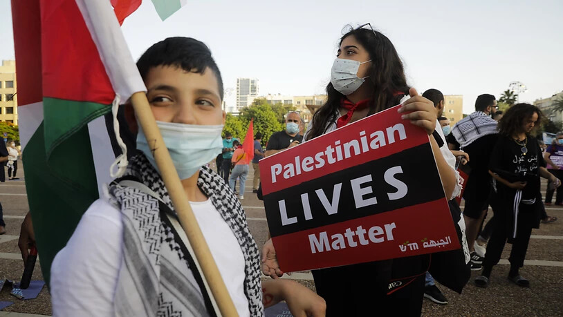 Eine Demonstrantin hält ein Schild mit einer Protestparole während eines Protests gegen die Pläne Israels, Teile des Westjordanlandes zu annektieren. Foto: Sebastian Scheiner/AP/dpa