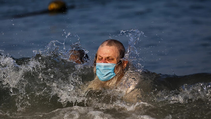 Ein Mann schwimmt mit Mundschutz an einem Strand in Tel Aviv. Foto: Oded Balilty/AP/dpa