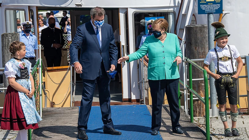 Markus Söder (CSU), Ministerpräsident von Bayern, empfängt an der Schiffsanlegestelle Prien Bundeskanzlerin Angela Merkel (CDU), um anschließend mit einem Schiff der Chiemsee-Schifffahrt auf die Insel Herrenchiemsee überzusetzen. Foto: Peter Kneffel/dpa…