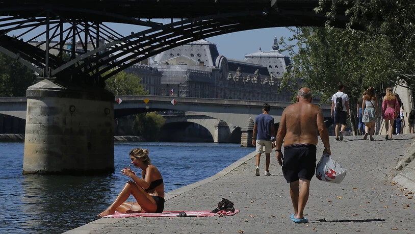 Menschen genießen das sonnige Wetter am Pariser Seineufer. Im Kampf gegen das Coronavirus gilt nun auch in Paris eine Maskenpflicht an zahlreichen öffentlichen Orten im Freien. Foto: Michel Euler/AP/dpa