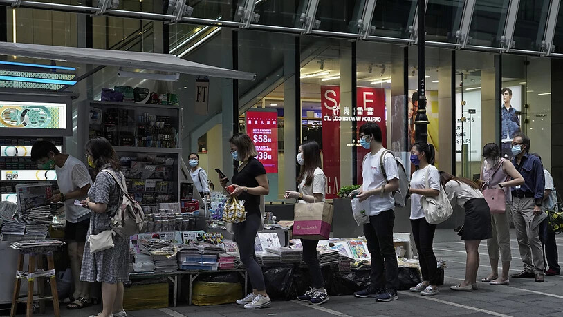 Menschen stehen an einem Zeitungsstand Schlange, um Exemplare der Zeitung Apple Daily zu kaufen. Foto: Vincent Yu/AP/dpa