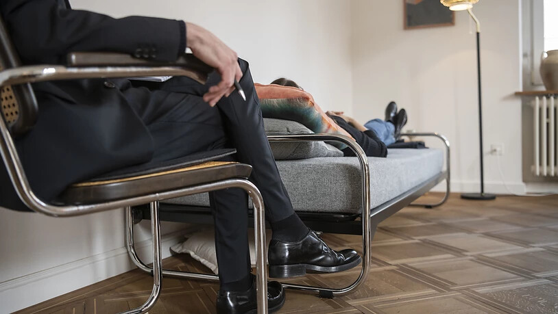[Gestellte Aufnahme] Ein Psychotherapeut, sitzend, therapiert in seiner Praxis eine Klientin, die auf einer Tagesbett liegt. (Archivbild)