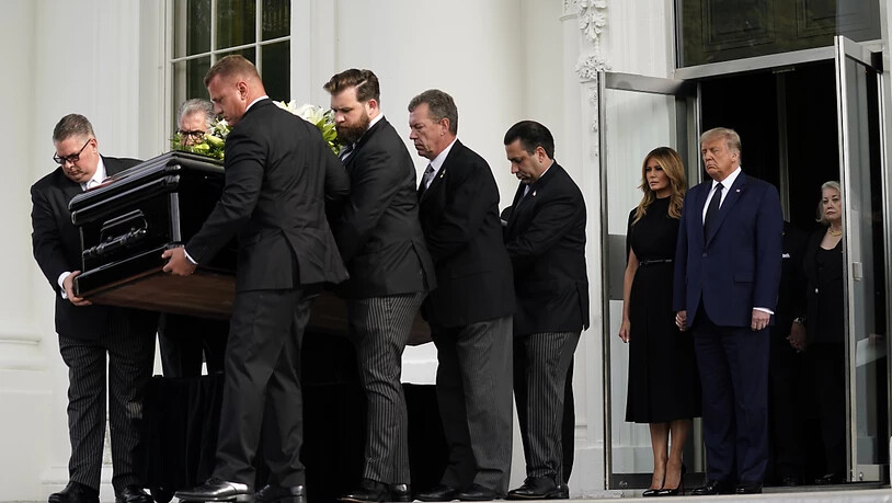 US-Präsident Donald Trump und First Lady Melania Trump stehen nebeneinander, während der Sarg von Robert Trump nach einer Gedenkfeier im Weißen Haus in einen Leichenwagen geladen wird. Foto: Evan Vucci/AP/dpa