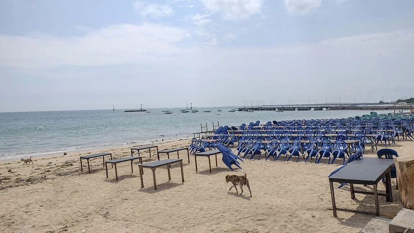 ARCHIV - Ein Hund läuft am Jimbaran Beach zwischen Tischen eines leeren Fischrestaurants. Als «Insel der Götter» ist Bali bei Surfern, Badegästen und Yogis aus aller Welt bekannt. Wegen Corona liegt die Reisebbranche seit Monaten am Boden. Foto: Wawan…