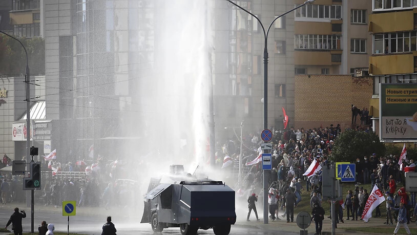 Polizisten setzten einen Wasserwerfer gegen Demonstranten ein. Trotz eines Großaufgebots an Sicherheitskräften haben Zehntausende Menschen gegen den autoritären Staatschef Lukaschenko demonstriert. Foto: Uncredited/AP/dpa