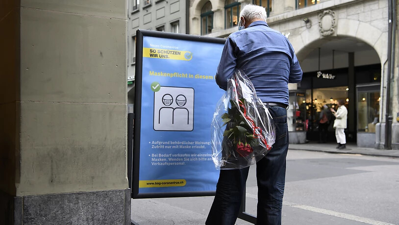 Ein Person steht in Bern vor einem Plakat mit den Verhaltensregeln des Bundesamtes fürr Gesundheit (BAG). (Symbolbild)