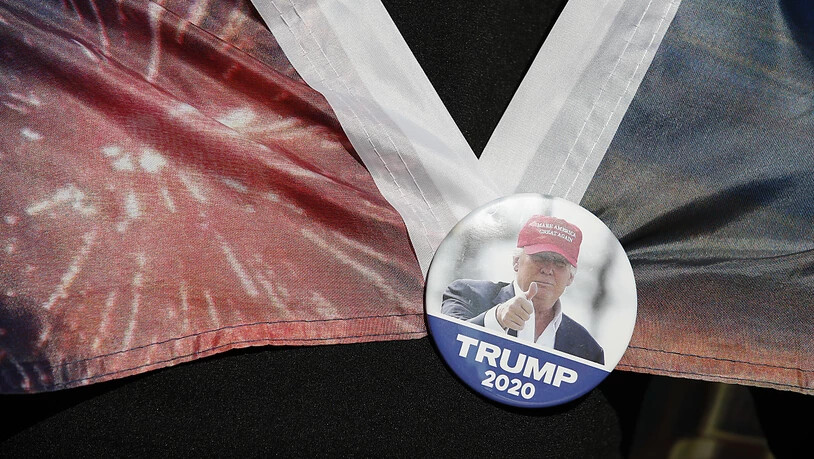 Eine Fraut trägt einen Button mit dem Bild des scheidenden US-Präsidenten Trump. Foto: Rebecca Blackwell/AP/dpa