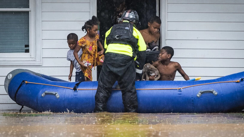 Ein Feuerwehrmann hilft Kindern beim Einstieg in ein Schlauchboot, da das Wohngebäude wegen des Hochwassers evakuiert werden muss. Der Tropensturm «Eta» zog mit starken Regenfällen über das Land hinweg. Foto: Andrew Dye/The Winston-Salem Journal/AP/dpa