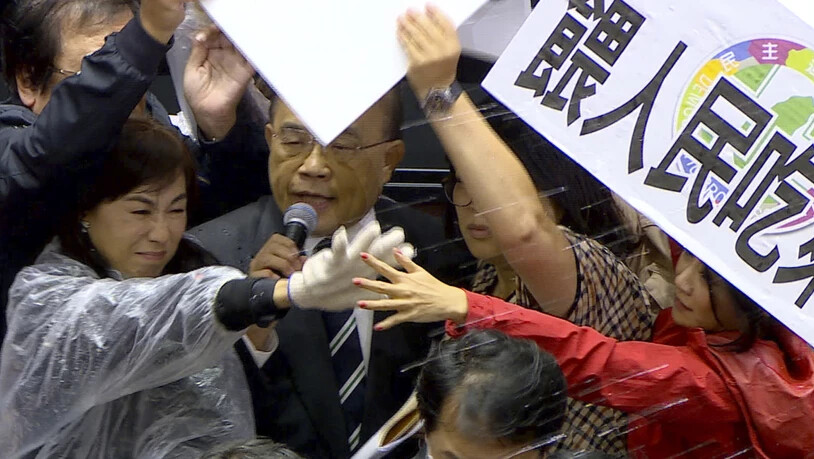 SCREENSHOT - Ministerpräsident Su Tseng-chang wird im Parlament mit Schweineinnereien beworfen. Foto: -/FTV/AP/dpa