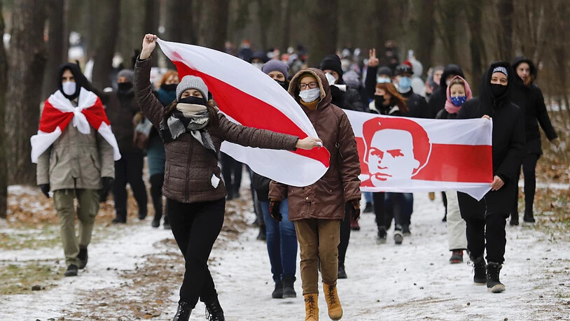 dpatopbilder - Demonstranten mit Mund-Nasen-Schutz tragen bei einer Kundgebung, auf der sie den Rücktritt von Machthaber Lukaschenko fordern, Fahnen in den Farben der früheren belarussischen Nationalflagge. Foto: ---/AP/dpa