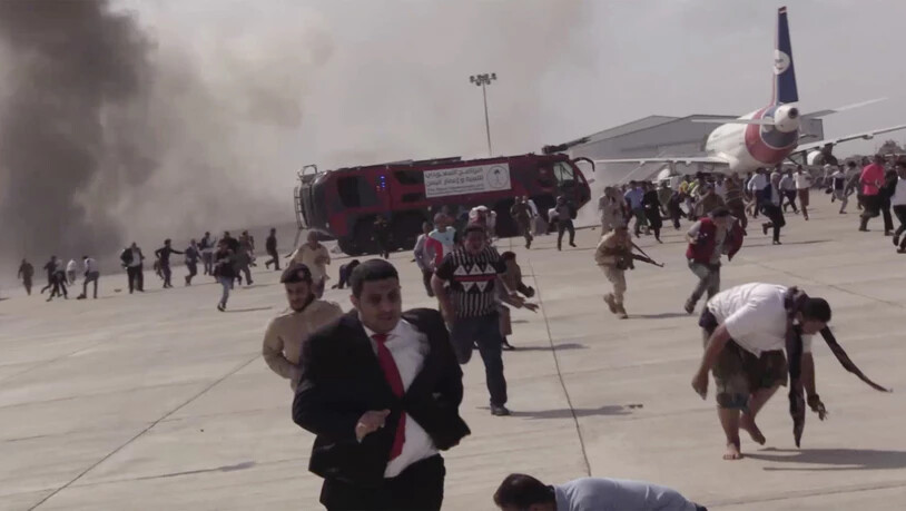 Menschen rennen nach einer schweren Explosion über den Flughafen. Der Vorfall ereignete sich Zeugenberichten zufolge kurz nach der Landung eines aus Saudi-Arabien kommenden Flugzeuges mit der neuen Regierung des Jemens. Foto: --/AP/dpa