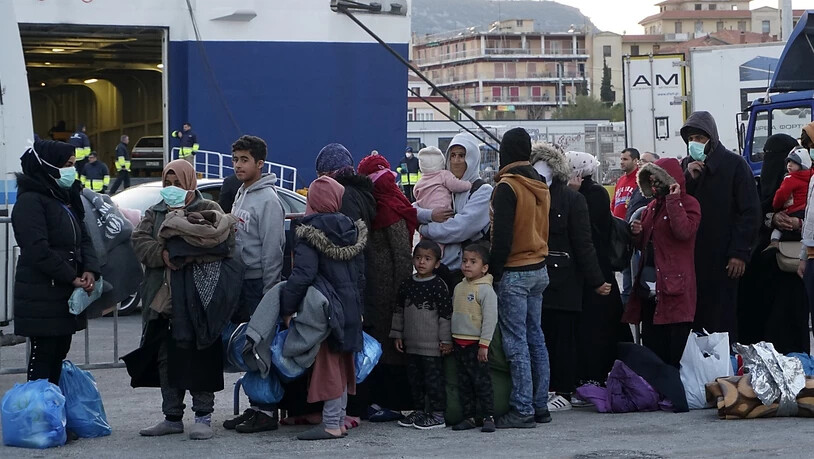 ARCHIV - Migranten stehen in einer Schlange, um im Hafen von Mytilene, auf der nordöstlichen Ägäisinsel Lesbos an Bord einer Fähre zu gehen. Foto: Vangelis Papantonis/AP/dpa