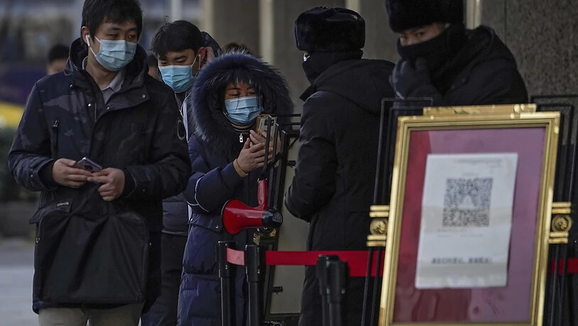 Menschen, die Gesichtsmasken tragen, scannen mit ihren Smartphones einen Code, bevor sie ein Bürogebäude betreten. Foto: Andy Wong/AP/dpa
