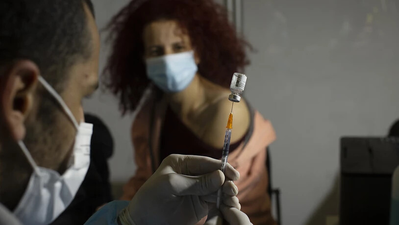 Eine medizinische Fachkraft bereitet sich darauf vor, einer Frau in einem Impfzentrum in einer Sportarena in Jerusalem den Impfstoff gegen Covid-19 von Pfizer-Biontech zu verabreichen. Foto: Maya Alleruzzo/AP/dpa