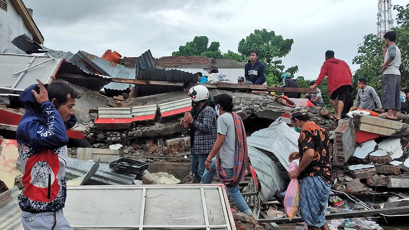 Anwohner auf der Insel Sulawesi inspizieren ein zerstörtes Haus. Foto: Yusuf Wahil/AP/dpa