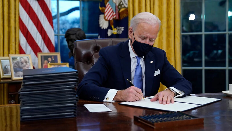 US-Präsident Joe Biden unterzeichnet seine erste Anordnung (Executive Order) im Oval Office des Weißen Hauses. Foto: Evan Vucci/AP/dpa