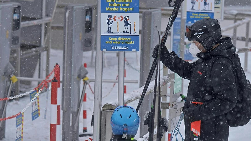 Skifahrer stehen vor einer Corona-Schleuse mit den Hinweisen, Abstand zu halten und eine Maske zu tragen, an einem Skilift im Skigebiet "Stuhleck" am Semmering in Niederösterreich. Foto: Herbert Pfarrhofer/APA/dpa