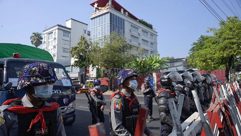 Polizisten sperren eine Straße in Rangun. Zahlreiche Menschen demonstrieren gegen den Militärputsch. Foto: Thet Htoo/ZUMA Wire/dpa