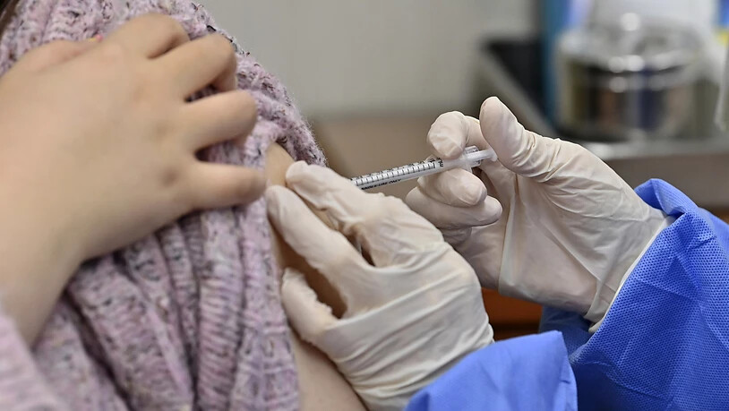 Ein Mitarbeiter eines Pflegeheims (l) erhält die erste Dosis des COVID-19-Impfstoffs von AstraZeneca. Südkorea hat mit den Impfungen gegen das Coronavirus begonnen. Foto: Jung Yeon-Je/AFP Pool/AP/dpa