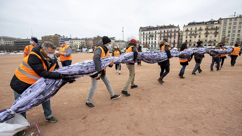 Freiwillige helfen mit die "We are watching"-Fahne in Genf zu entfalten. Quelle: KEYSTONE Fotograf: MARTIAL TREZZINI