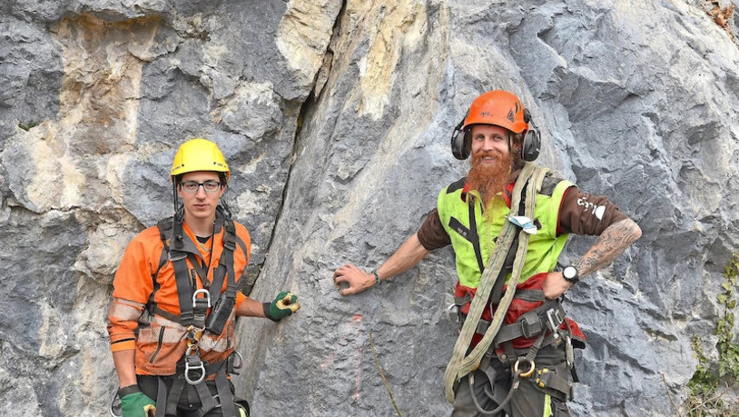 Steinschlaggebiet: Der Netstaler Alex Finella (gelber Helm) und Samuel Bruderer vom Forstbetrieb Amden räumen Steine aus den Fangnetzen und werfen sie in den Walensee, weshalb die Betliserstrasse für Spaziergänger derzeit nur beschränkt passierbar ist.