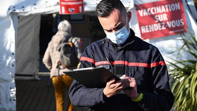 Ein Feuerwehrmann mit Mund-Nasen-Bedeckung steht vor einer Feuerwehrwache im französischen Vailhauquès, die in ein temporäres Corona-Impfzentrum umgewandelt wurde. Foto: Pascal Guyot/AFP/dpa