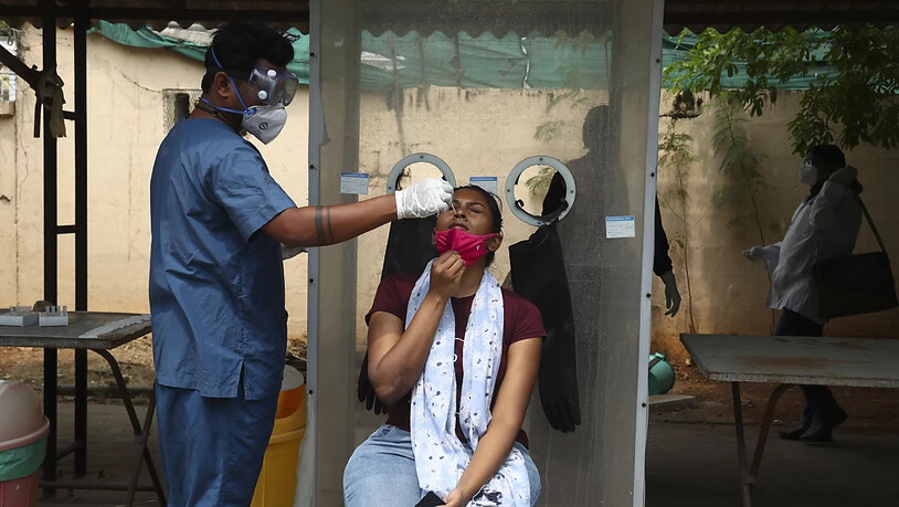 Ein Mitarbeiter des Gesundheitswesens entnimmt einer Frau einen Nasenabstrich. Foto: Mahesh Kumar A/AP/dpa