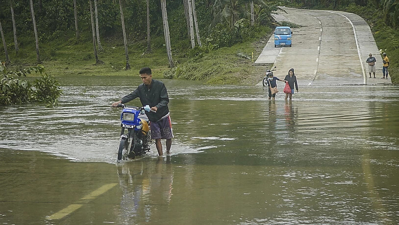 Bewohner überqueren eine überflutete Straße auf den Philippinen. Die Überflutungen wurden durch den Regen des Taifuns "Surigae" verursacht, der bisher mindestens sieben Menschenleben gefordert hat. Foto: Uncredited/AP/dpa