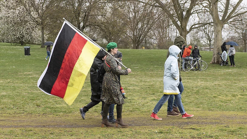 Teilnehmer der Demonstration der Initiative «Querdenken» mit einer Deutschlandfahne. Foto: Boris Roessler/dpa