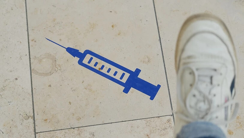ARCHIV - Das Symbol einer Spritze ist auf dem Boden der Muldentalhalle in Sachsen aufgeklebt. Foto: Sebastian Willnow/dpa-Zentralbild/dpa