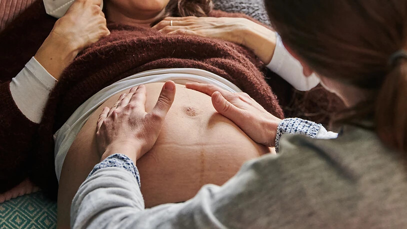 ARCHIV - Eine Hebamme tastet in ihrer Praxis den Bauch einer schwangeren Frau ab. Foto: Annette Riedl/dpa