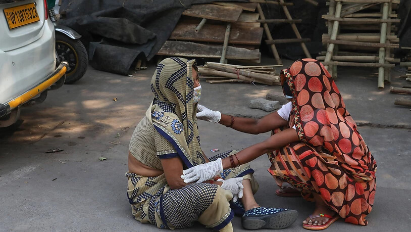 Die Angehörige eines Covid-19-Opfers wird während der Einäscherung des Leichnams im Krematorium Nigambodh Ghat in Neu-Delhi getröstet. Foto: Naveen Sharma/SOPA Images via ZUMA Wire/dpa