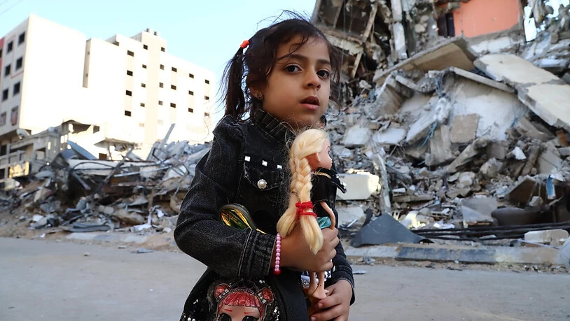 dpatopbilder - Ein Mädchen geht vorbei an von Luftangriffen zerstörten Häusern. Seit dem 10. Mai beschießen militante Palästinenser Israel mit Raketen. Israels Armee reagiert darauf mit Angriffen auf Ziele im Gazastreifen, vor allem durch die Luftwaffe…