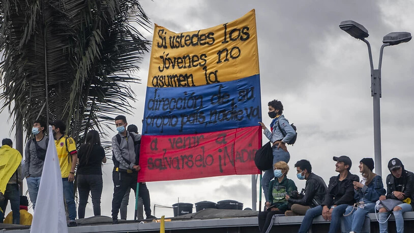 Menschen tragen eine kolumbianische Flagge, auf der geschrieben steht: "Wenn ihr jungen Leute nicht die Führung eures eigenen Landes übernehmt, wird niemand kommen, um euch zu retten, niemand". Foto: Daniel Garzon Herazo/ZUMA Wire/dpa