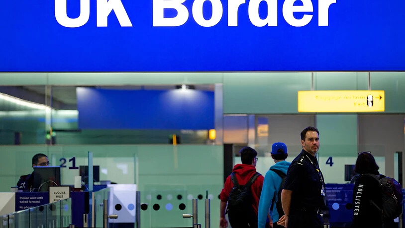 ARCHIV - Grenzbeamte stehen am Flughafen Heathrow unter einem Schild mit der Aufschrift «UK Border» (Grenze des Vereinigten Königreiches). Foto: Andrew Cowie/EPA/dpa