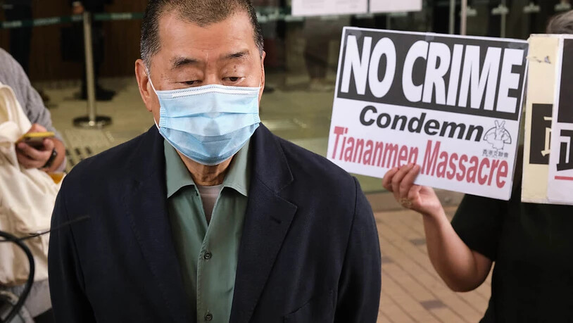 ARCHIV - Ein Unterstützer hält ein Schild mit der Aufschrift «No Crime - Condemn Tiananmen Massacre» (Kein Verbrechen - Tiananmen Massaker verurteilen) in der Hand, als der regierungskritische Medienunternehmer Jimmy Lai am Amtsgericht von West Kowloon…