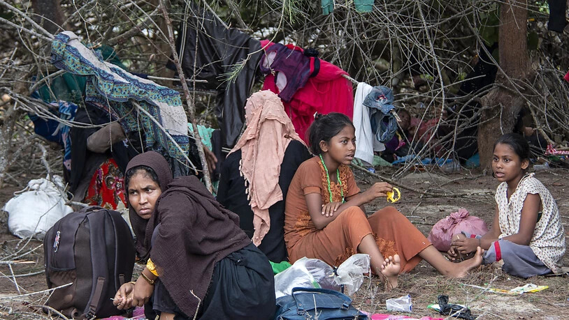 Geflüchtete Rohingya ruhen sich in der Nähe eines Strandes am Boden aus, nachdem ihre Boote an den Andamanen gestrandet war. Nach Monaten auf See sind Dutzende Flüchtlinge der muslimischen Minderheit der Rohingya aus Myanmar in Indonesien gelandet. Foto:…