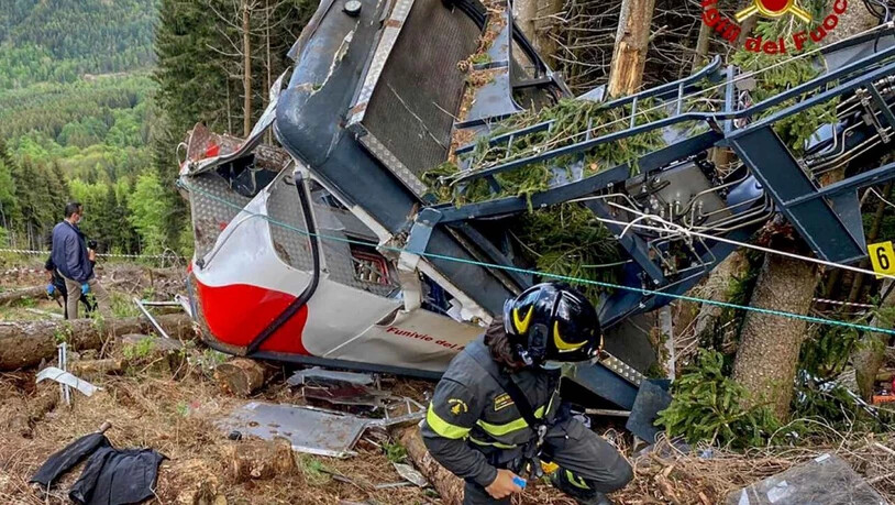 HANDOUT - Rettungskräfte arbeiten am Wrack einer abgestürzten Gondel, die in einem Waldstück liegt. Nach dem Seilbahnunglück in Italien soll die Unglücksgondel mit einem Hubschrauber abtransportiert werden. Foto: Uncredited/Vigili del Fuoco Firefighters…