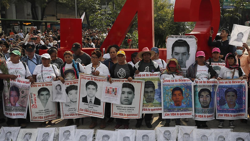 ARCHIV - Angehörige der 43 vermissten Lehramtsstudenten halten 2019 bei einem Protestmarsch Porträts der Vermissten. Foto: Marco Ugarte/AP/dpa