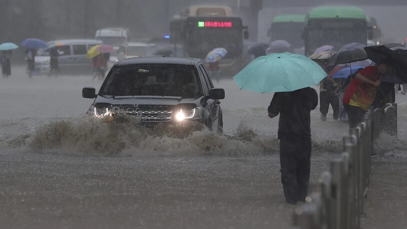Ein Auto fährt in der zentralchinesischen Provinz Henan über eine überflutete Straße. Foto: Yuanxiaoqiang/CHINATOPIX/AP/dpa