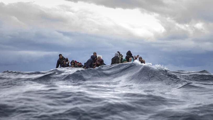 ARCHIV - Männer sitzen in einem überfüllten Holzboot im Mittelmeer vor der Küste von Libyen (Archivbild). Foto: Santi Palacios/AP/dpa