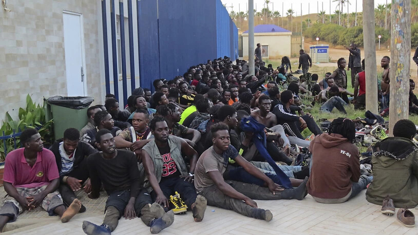 Eine Gruppe von Migranten sitzt in einem Aufnahmezentrum in Melilla. Insgesamt 238 Menschen sind am frühen Donnerstagmorgen über den Grenzzaun zwischen Marokko und Spanien gesprungen. Dabei seien laut Angaben des TV-Senders RTVE drei spanische Polizisten…